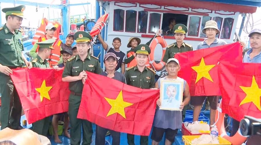 Bộ đội Biên phòng tỉnh Gia Lai tặng cờ Tổ quốc và ảnh Bác Hồ cho ngư dân. Ảnh: C.Cường
