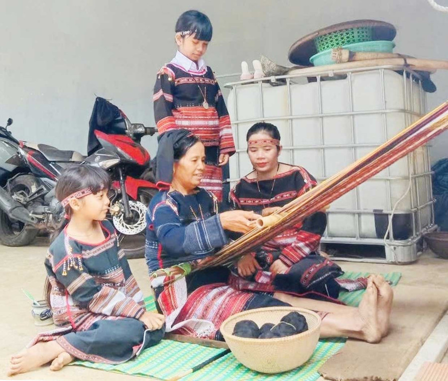 Bà Đinh Thị Hiền chỉ cho các con, cháu kỹ thuật dệt thổ cẩm. Ảnh: H.T Bà Đinh Thị Hiền chỉ cho các con, cháu kỹ thuật dệt thổ cẩm.