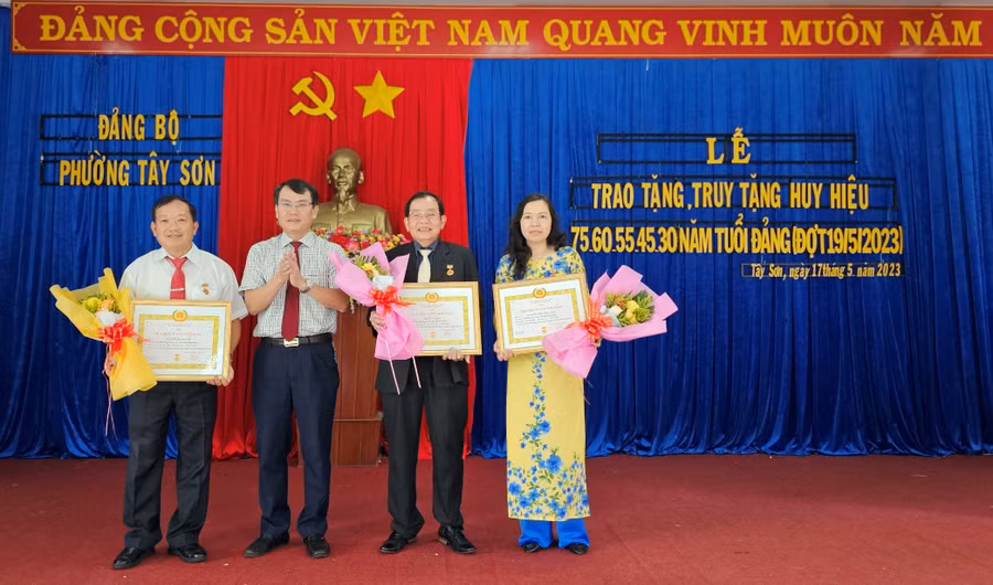 Bí thư Thành ủy Trịnh Duy Thuân (thứ 2 từ trái qua) trao Huy hiệu Đảng và tặng hoa chúc mừng các đảng viên. Ảnh: Anh Huy