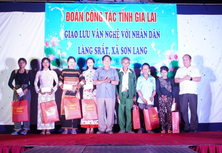 Phó Bí thư Tỉnh ủy Rah Lan Chung (ngoài cùng bên phải) và đồng chí Hà Sơn Nhin (thứ 5 từ trái qua) tặng quà cho người dân làng Srắt và làng Đăk A Sêl. Ảnh: Đức Thụy