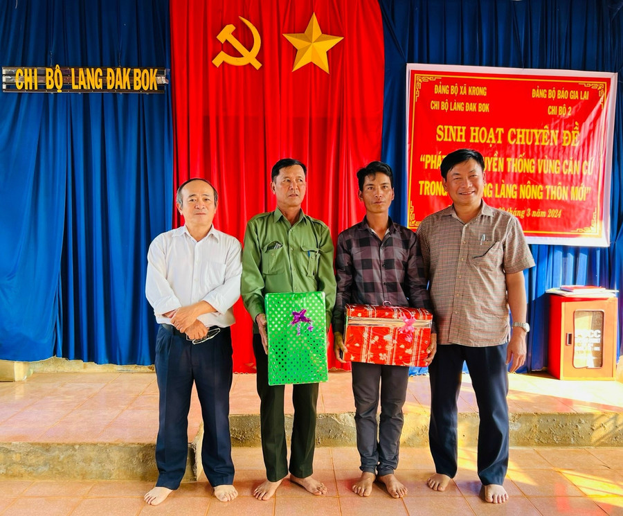 Bí thư Đảng ủy, Tổng Biên tập Báo Gia Lai Huỳnh Kiên (ngoài cùng bên phải) và Bí thư Chi bộ 2 Võ Thành Thất (ngoài cùng bên trái) tặng quà chi bộ làng Đak Bok. Ảnh: P.D