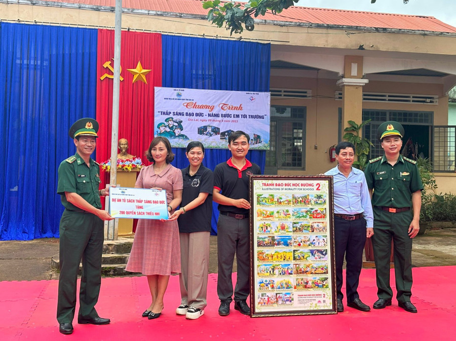 Đại diện Bộ Chỉ huy Bộ đội Biên phòng tỉnh và Câu lạc bộ "Vòng tay yêu thương" trao tặng tủ sách và bộ tranh đạo đức học đường cho đại diện nhà trường. Ảnh: Kiên Quyết Đại diện Bộ Chỉ huy Bộ đội Biên phòng tỉnh và Câu lạc bộ "Vòng tay yêu thương" trao tặng tủ sách và bộ tranh đạo đức học đường cho đại diện nhà trường. Ảnh: Kiên Quyết