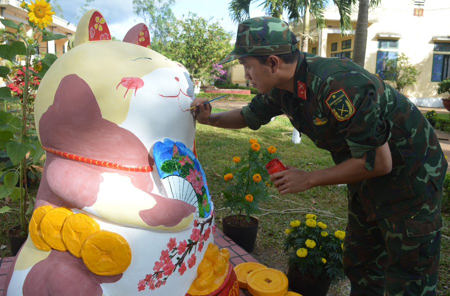 Thiếu úy Hồ Trọng Hiếu tỉ mỉ vẽ từng chi tiết trên khuôn mặt linh vật mèo thần tài. Ảnh: Anh Huy