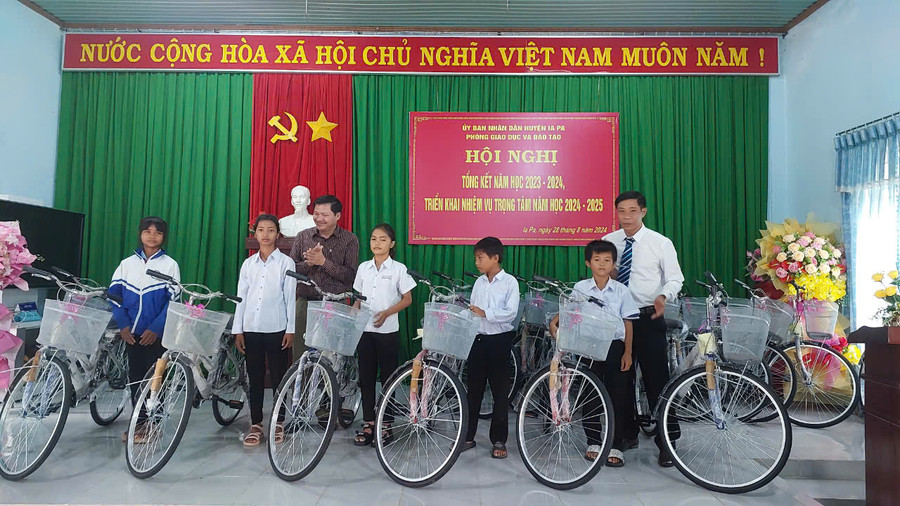 Phó Chủ tịch Thường trực HĐND tỉnh (áo xám bìa trái) cùng Bí thư Huyện ủy Ia Pa Nguyễn Minh Trưởng tặng xe đạp cho các em học sinh. Ảnh: Nguyễn Diệp