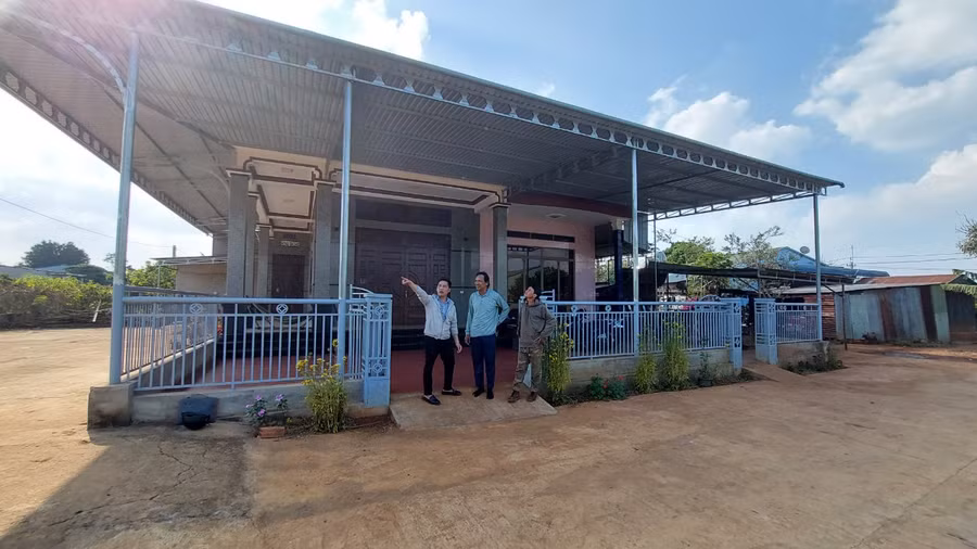 Ông R'com Hne (đứng giữa) bên căn nhà của gia đình cùng lãnh đạo UBND xã và Bí thư chi bộ kiêm thôn trưởng. Ảnh: Nguyễn Diệp