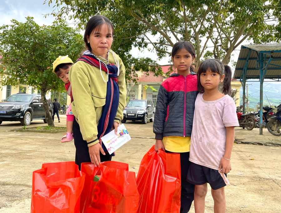 Chị Đinh Thị Dơh-một trong số hộ nghèo của làng Mèo (xã Đak Pling) địu theo con nhỏ có mặt từ rất sớm để nhận phần quà Tết nghĩa tình. Ảnh: Minh Phương