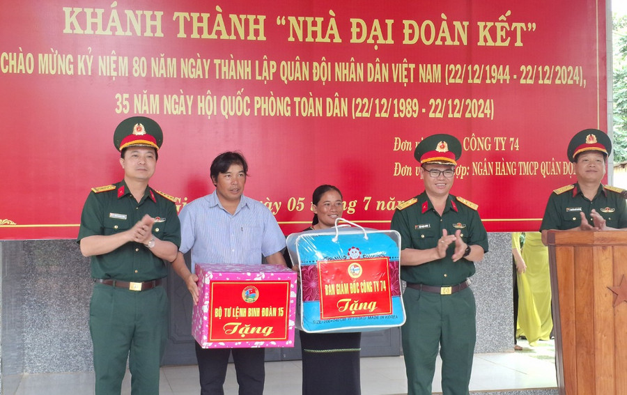 Lãnh đạo Binh đoàn 15, Công ty 74 trao tặng quà cho gia bà Rơ Mah Pen trong buổi lễ khánh thành nhà Đại đoàn kết. Ảnh: T.D