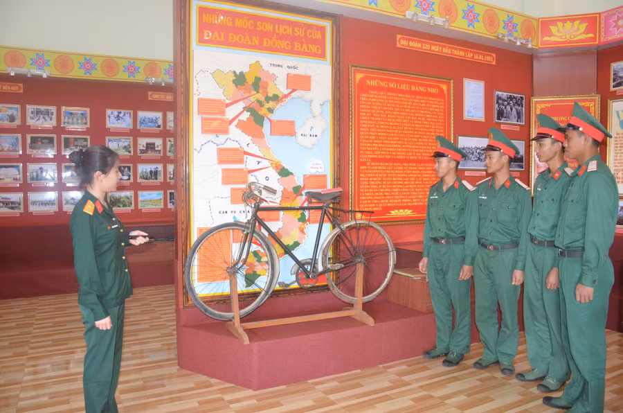 Nhân viên nhà truyền thống Sư đoàn 320 giới thiệu về chiếc xe đạp. Ảnh: Vĩnh Hoàng