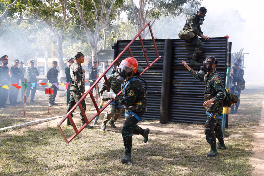 Các vận động viên mang vác thiết bị, thực hiện phần thi vượt chướng ngại vật phải đeo đồ phòng-chống độc. Ảnh: Vĩnh Hoàng