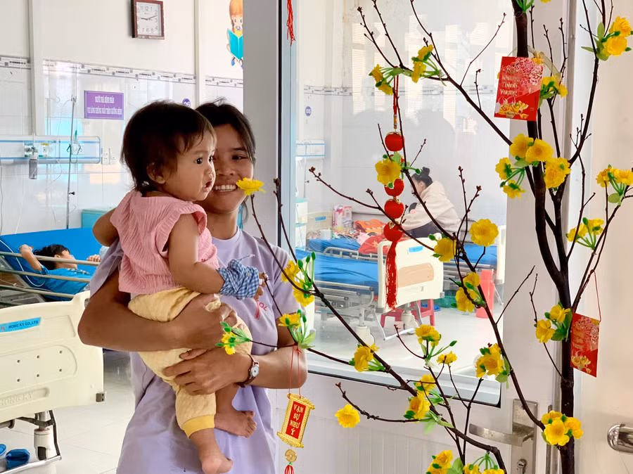 Một bệnh nhi thích thú cùng mẹ ngắm mai vàng. Ảnh: Như Nguyện