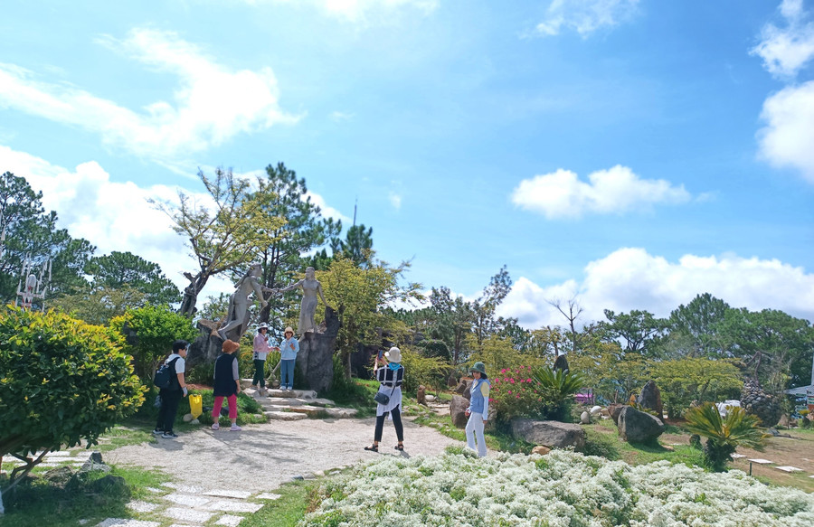 Du khách chụp ảnh lưu niệm bên tượng của chàng K’lang và nàng H’biang cũng như tìm hiểu về chuyện tình đẹp nhưng đầy bi ai. Ảnh: Quang Tấn