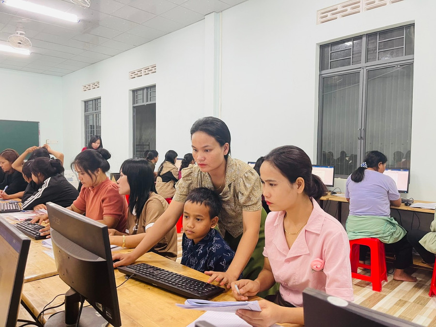 Chị H&apos;Tinh chỉ cho con trai cách soạn thảo văn bản tại lớp học. Ảnh: Nhật Hào