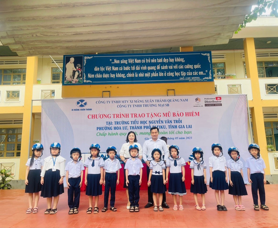 Đại diện Công ty TNHH một thành viên xi măng Xuân Thành Quảng Nam và lãnh đạo nhà trường tặng mũ bảo hiểm cho các em học sinh. Ảnh: Nhật Hào