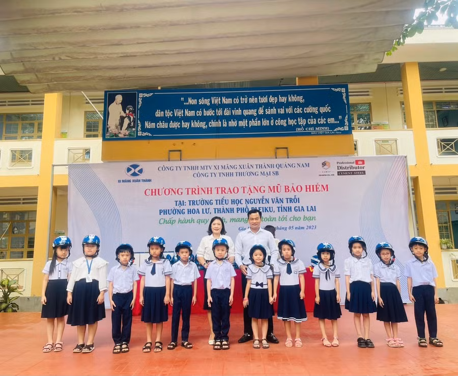 Đại diện Công ty TNHH một thành viên xi măng Xuân Thành Quảng Nam và lãnh đạo nhà trường tặng mũ bảo hiểm cho các em học sinh. Ảnh: Nhật Hào