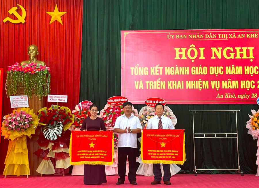 Phó Bí thư Thị ủy, Chủ tịch UBND thị xã An Khê Đinh Văn Cương (đứng giữa) trao cờ thi đua của UBND tỉnh cho 2 tập thể có thành tích xuất sắc trong phong trào thi đua yêu nước năm học 2022-2023. Ảnh: Ngọc Minh Phó Bí thư Thị ủy, Chủ tịch UBND thị xã An Khê Đinh Văn Cương (đứng giữa) trao cờ thi đua của UBND tỉnh cho 2 tập thể có thành tích xuất sắc trong phong trào thi đua yêu nước năm học 2022-2023. Ảnh: Ngọc Minh