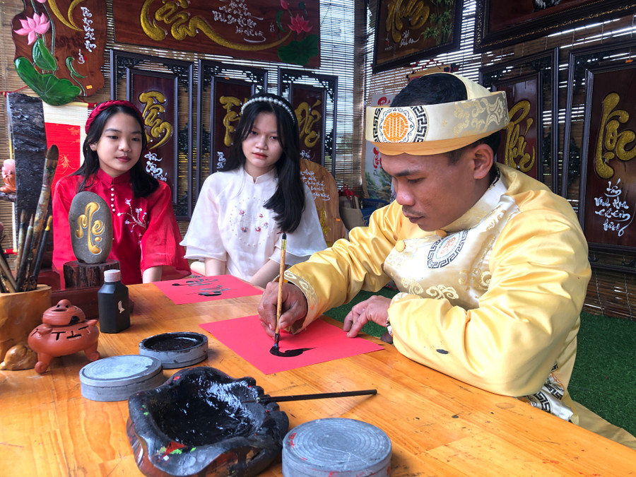 Em Nguyễn Thùy Dương (thứ 2 bên trái ở thôn Chí Công, xã Cư An, huyện Đak Pơ) đã chủ động nhờ &quot;ông đồ&quot; viết cho chữ: Cha, mẹ. Ảnh: Ngọc Minh