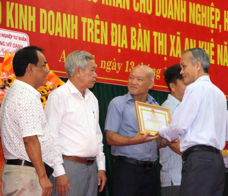 Phó Bí thư Thị ủy, Chủ tịch UBND thị xã An Khê Nguyễn Hùng Vỹ (bìa phải) tặng giấy khen cho tập thể, hộ kinh doanh. Ảnh: Ngọc Minh