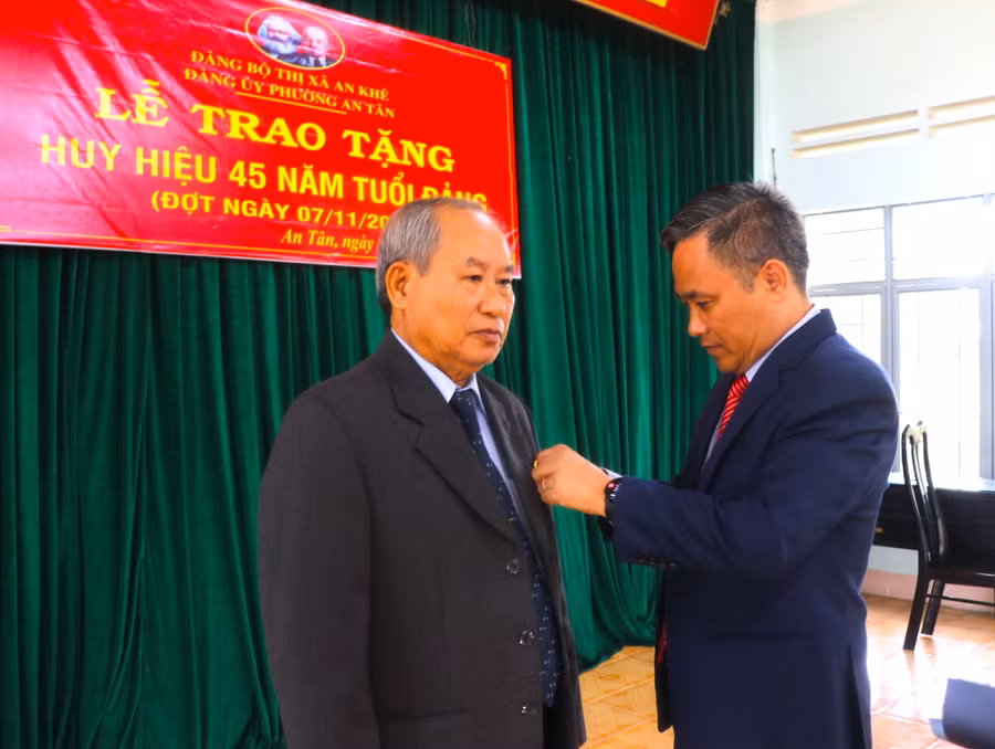 Bí thư Thị ủy An Khê Nguyễn Xuân Phước (bìa phải) trao Huy hiệu 45 năm tuổi Đảng cho đồng chí Nguyễn Ngọc Tuấn-nguyên Tỉnh ủy viên, Bí thư Thị ủy, Chủ tịch HĐND thị xã An Khê. Ảnh: Ngọc Minh