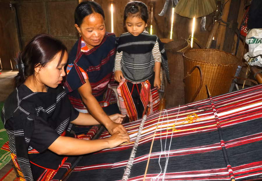 Tranh thủ những lúc nông nhàn, sớm tối, các bà, các mẹ ở làng Pốt, xã Song An, thị xã An Khê lại cần mẫn hướng dẫn con em mình dệt vải. Ảnh: Ngọc Minh