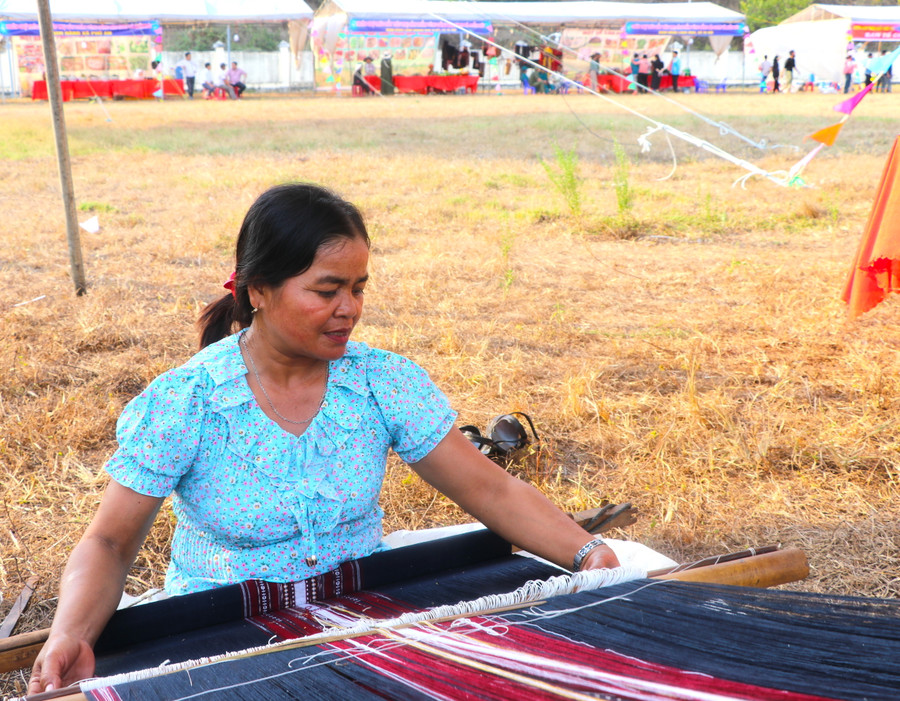 Bà Đinh Thị Đáp (làng Kuk Đak, xã An Thành, huyện Đak Pơ) trình diễn dệt thổ cẩm tại hội chợ. Ảnh: Ngọc Minh