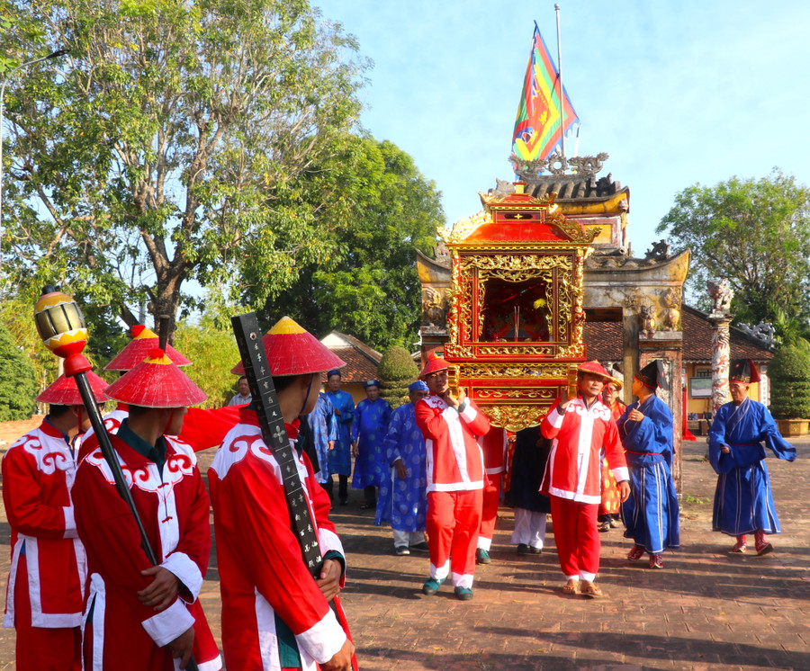 Sắc thần được để bên trong long đình. Ban Nghi lễ đình An Khê cùng các bô lão, đội nghênh long đình, nghinh sắc thần đi qua nhà ngõ trước An Khê trường. Dẫn đầu đoàn nghinh sắc thần là vị trưởng lão cùng đội nghênh long đình, cầm cờ ngũ hành, binh khí trong trang phục binh lính thời xưa, đầu đội nón, oai phong tiến về phía trước. Kế đến là các chức sắc, người dân trong vùng theo sau. Ảnh: Ngọc Minh