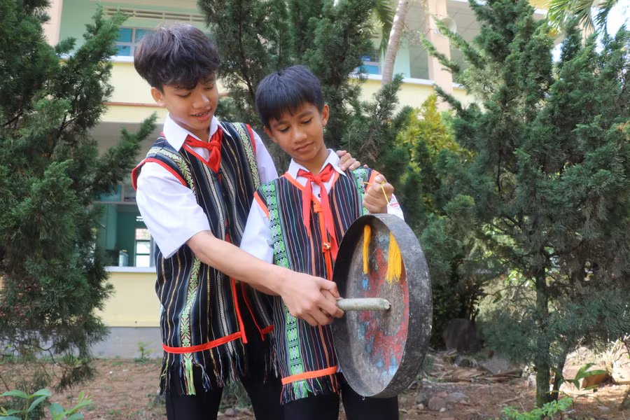 Em Lô Minh Trí (bìa trái, lớp 9) hướng dẫn cách đánh cồng chiêng cho em Đinh Sơn Thái (lớp 6). Ảnh: Ngọc Minh