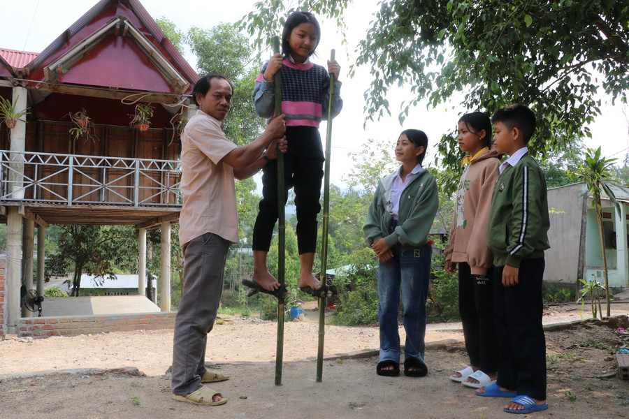 Tranh thủ những lúc nông nhàn, ông Đinh Văn Nhin lại dạy thiếu niên trong làng cách giữ thăng bằng trên cà kheo. Ảnh: Ngọc Minh