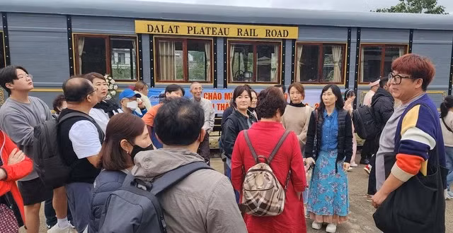 Người đàn ông (ngoài cùng bên phải), hướng dẫn nhóm du khách Hàn Quốc tham quan ga xe lửa Đà Lạt.