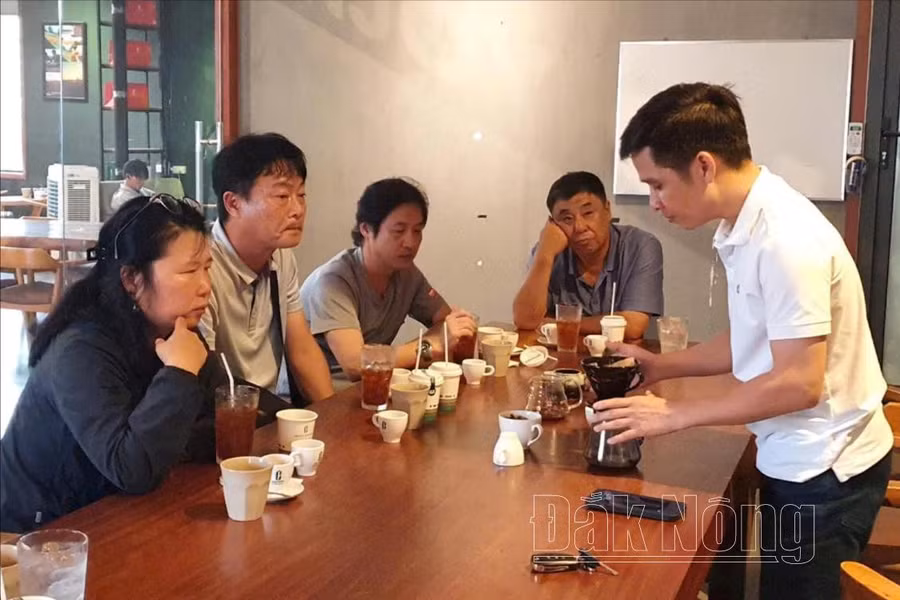 Anh Lê Văn Hoàng (bên phải) Giám đốc Công ty Cà phê Bazan Đắk Nông chia sẻ cho đoàn du khách đến từ Hàn Quốc về trải nghiệm nếm cà phê do anh Long làm hướng dẫn viên du lịch