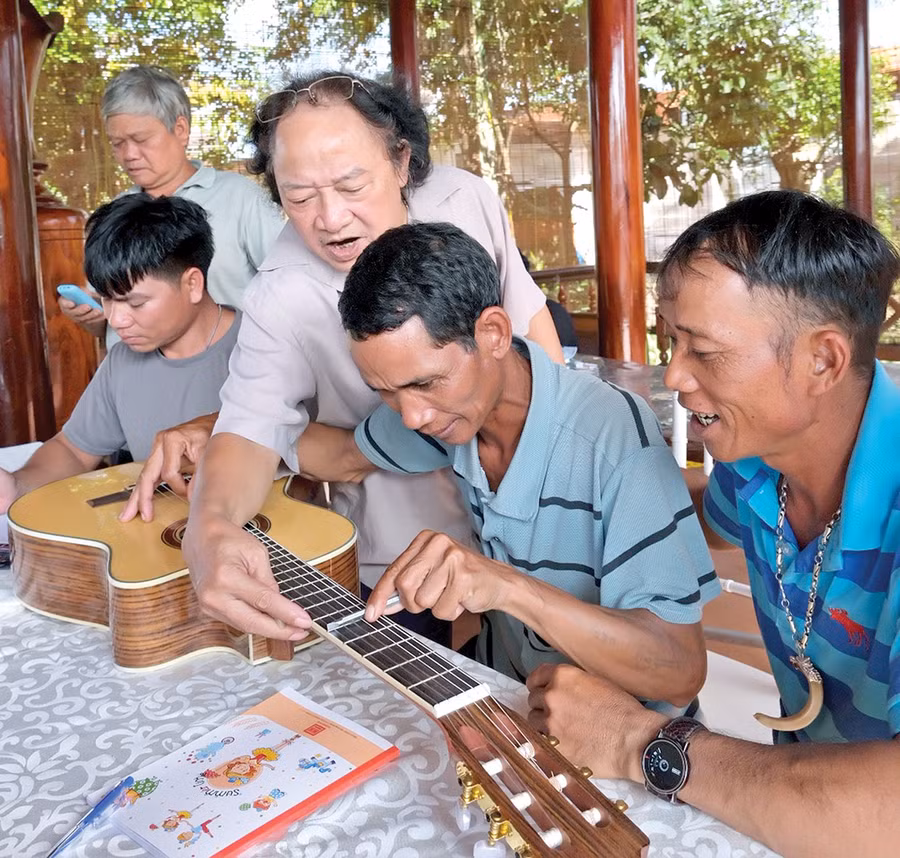 Các chuyên gia dùng đàn guitar làm thước để hướng dẫn nghệ nhân cách đo thang âm cồng chiêng. Ảnh: H.N