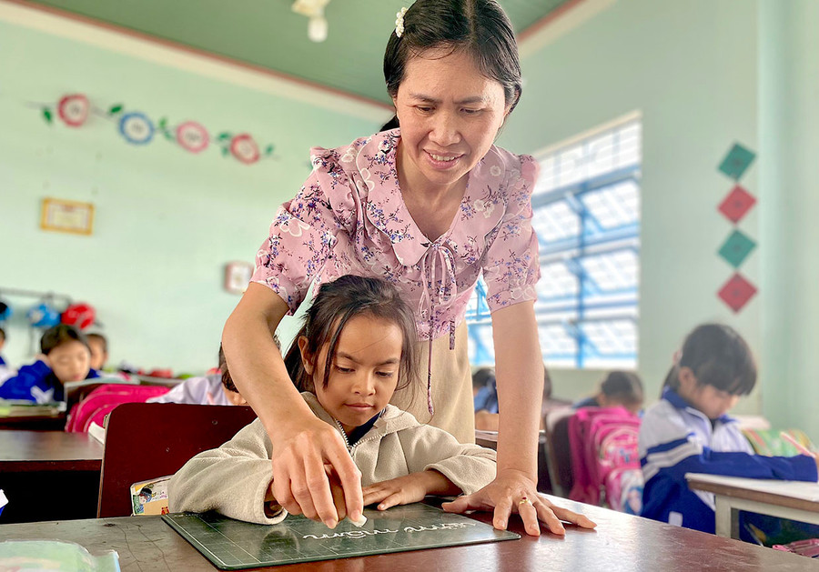 Cô Yến giúp học trò viết chữ trên bảng con. Ảnh: Mộc Trà Cô Yến giúp học trò viết chữ trên bảng con. Ảnh: Mộc Trà
