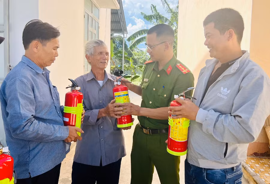 Cán bộ Công an xã Tú An hướng dẫn người dân sử dụng bình chữa cháy. Ảnh: N.H