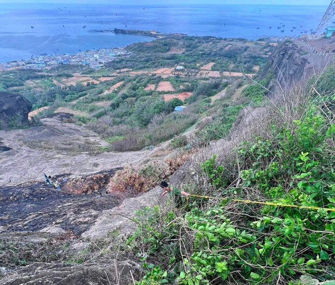Cảnh sát bám dây để trèo xuống vực tìm kiếm các vật dụng liên quan vụ việc. Ảnh: DT