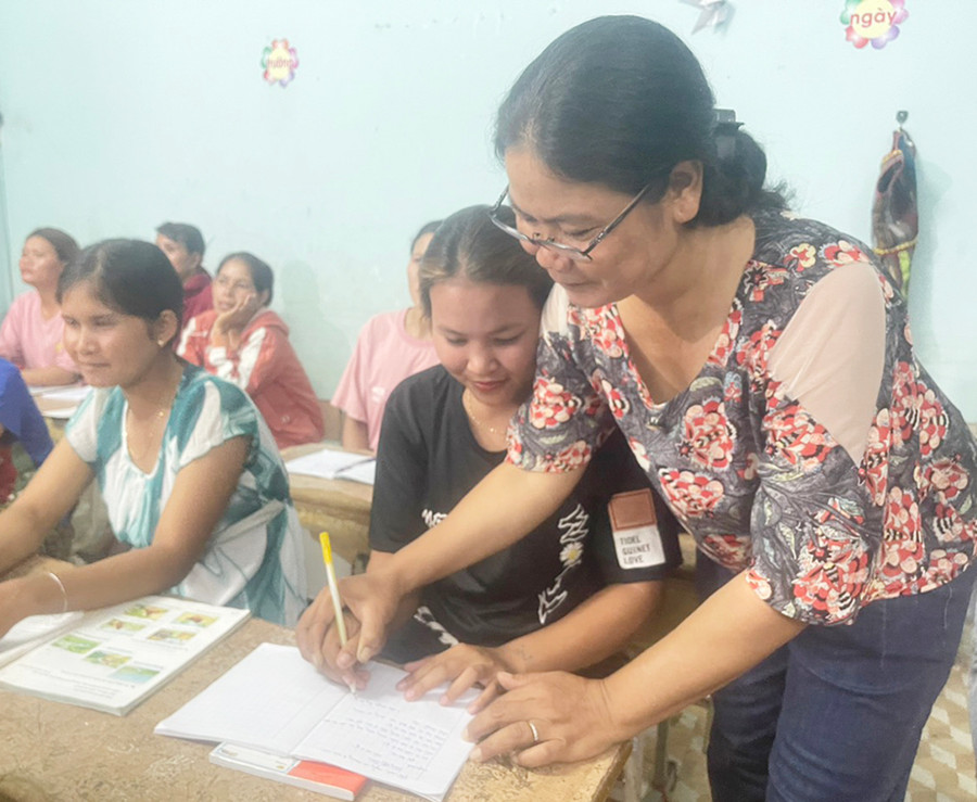 Cô Ksor H’Đơi hướng dẫn học viên lớp xóa mù chữ buôn Mơ Nai Trang tập viết. Ảnh: V.C Cô Ksor H’Đơi hướng dẫn học viên lớp xóa mù chữ buôn Mơ Nai Trang tập viết. Ảnh: V.C