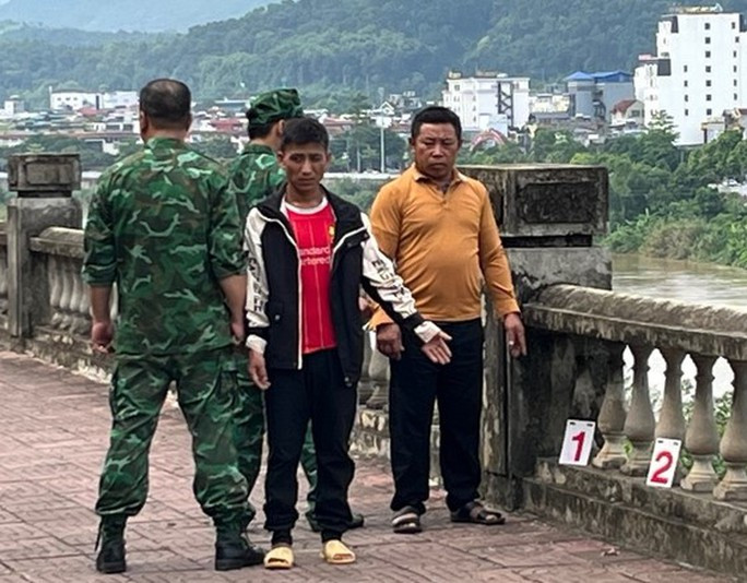 Cô gái trẻ bị người yêu lừa bán sang Trung Quốc - Ảnh 1. Thào A Dờ (áo đỏ) và Sùng A Sì đang thực nghiệm lại hành vi phạm tội của mình. Ảnh: Theo Báo Lào Cai