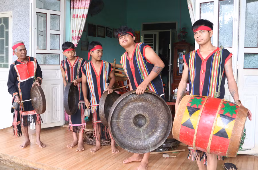 Nghệ nhân Ak (bìa trái) truyền dạy cồng chiêng cho thanh-thiếu niên trong làng. Ảnh: Q.T