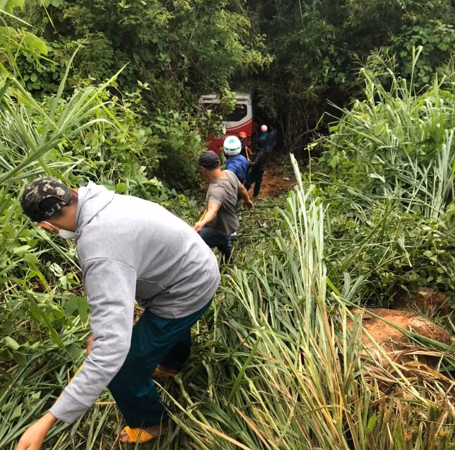 Người dân và hành khách cố gắng kéo chiếc xe gặp nạn lên khỏi vực đèo. Ảnh: Phạm Duy