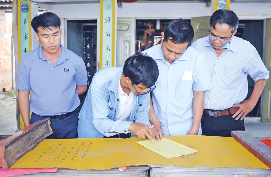 Tiến sĩ Lưu Hồng Sơn (thứ 2 từ trái sang) giải mã văn tự Hán-Nôm trên sắc thần tại đình Tân Tạo (xã Thành An, thị xã An Khê). Ảnh: Huỳnh Bá Tính
