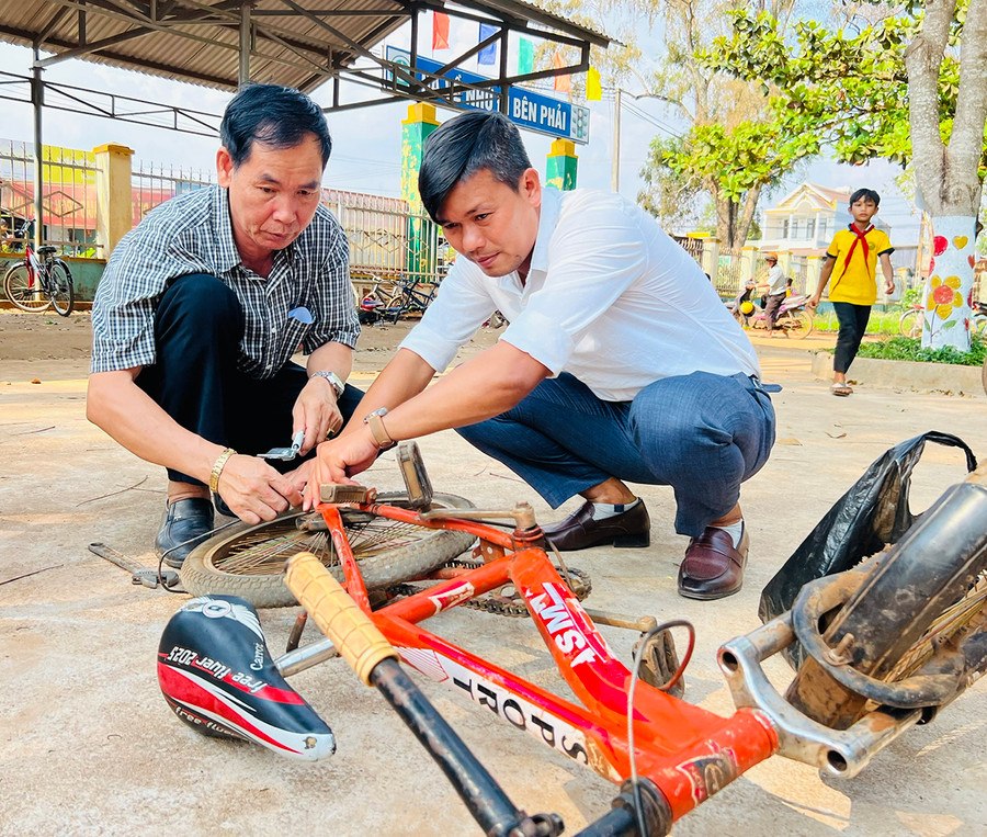 Thầy Trương Thanh Tùng (bìa phải) và thầy Lê Văn Hoạt sửa xe đạp cho học sinh Trường Tiểu học Bùi Thị Xuân. Ảnh: Minh Nhật