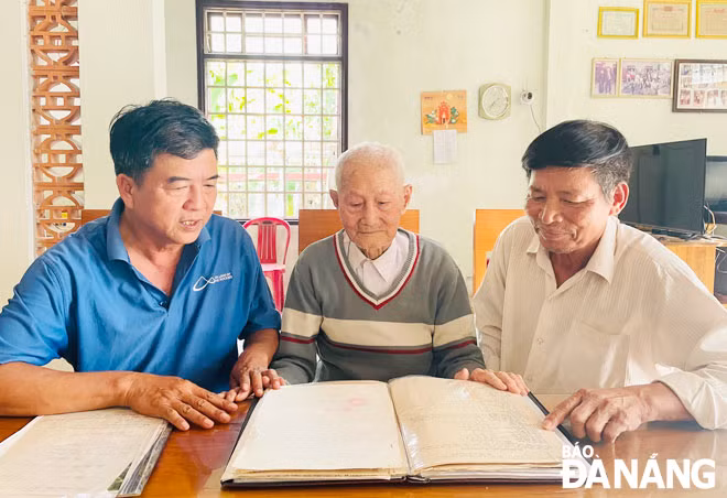 Cụ ông Hà Thúc Duyên (giữa) cùng nguyên trưởng thôn Trung Sơn Võ Chí Thanh (bên phải) và trưởng thôn Hà Thúc Vinh xem lại tư liệu rừng Trung Sơn được cụ Duyên lưu giữ. Ảnh: H.T.V
