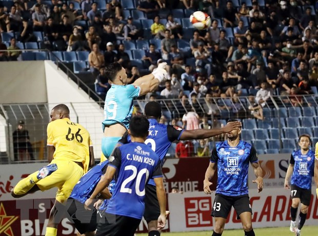 Pha bay người cản phá bóng thành công của thủ môn đội Thành phố Hồ Chí Minh trong trận hòa Quảng Nam ở Vòng 2. (Ảnh: Trần Lê Lâm/TTXVN)