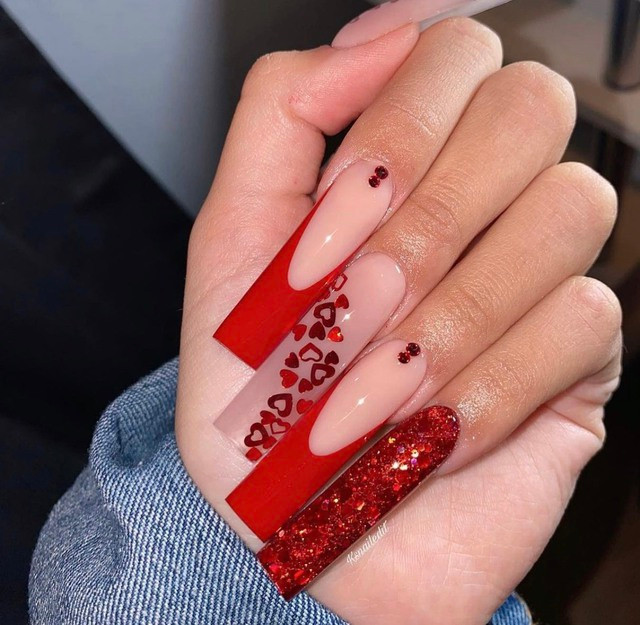 Valentine không thể thiếu những mẫu nail màu đỏ. Và bạn sẽ trở nên quyến rũ, sang chảnh hơn trong nháy mắt với thiết kế nail đỏ phối nhũ, gắn đá và dán sticker hình trái tim.