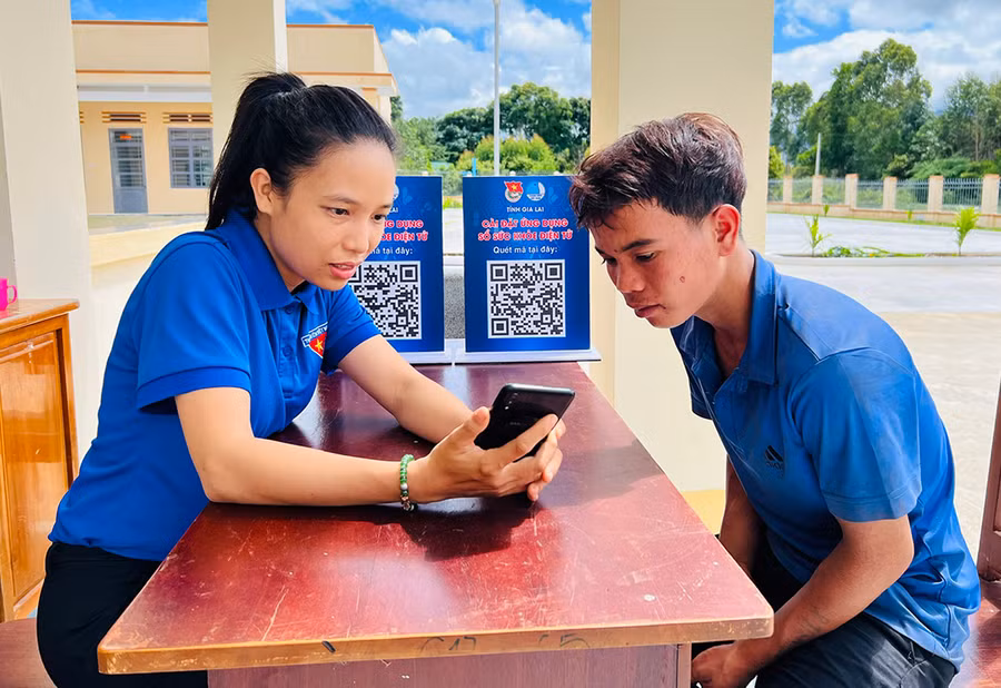 Đoàn viên, thanh niên hướng dẫn người dân xã Đak Jơ Ta cài đặt ứng dụng sổ sức khỏe điện tử. Ảnh: Minh Nhật