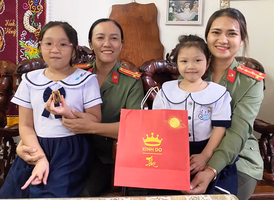 Cán bộ Hội Phụ nữ Công an tỉnh thăm hỏi, tặng quà cháu Lâm Ngọc Gia Linh (bìa trái) và Lâm Ngọc An Nhiên. Ảnh: R.H