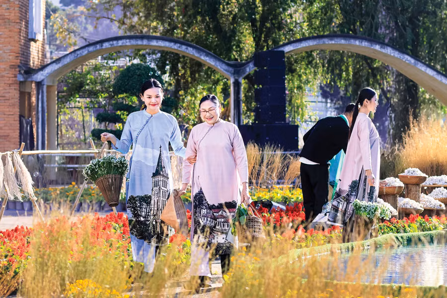 Các mẹ, các chị mặc trang phục áo dài cách tân in hình những phong cảnh kiến trúc đặc sắc của Đà Lạt đang đi chợ, đựng rau, hoa trong những chiếc giỏ cổ độc đáo
