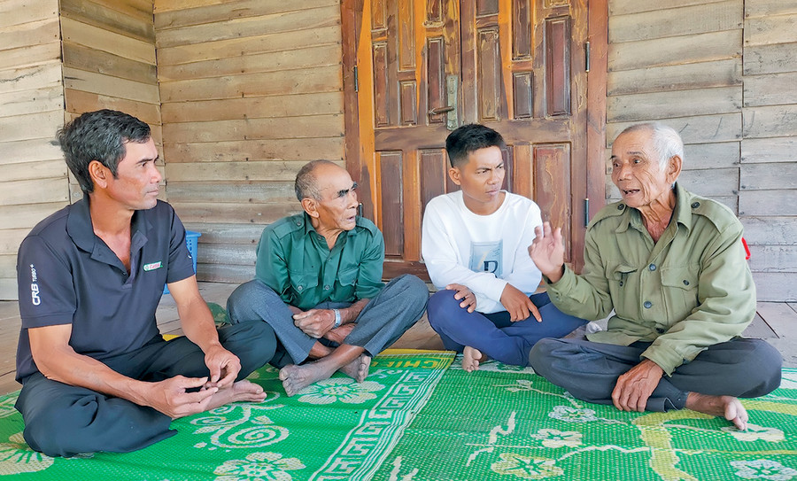 Ông Đinh Êu (bìa phải) kể lại câu chuyện về người chú họ Đinh Đây-Bí thư Chi bộ đầu tiên của làng Krông Hra. Ảnh: H.T Ông Đinh Êu (bìa phải) kể lại câu chuyện về người chú họ Đinh Đây-Bí thư Chi bộ đầu tiên của làng Krông Hra. Ảnh: H.T