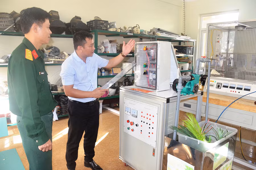 Thầy giáo Trần Phú Quý (bên phải) giới thiệu thiết bị “Hệ thống điều khiển động cơ bơm nước 1 pha theo 4 chế độ”. Ảnh: T.T