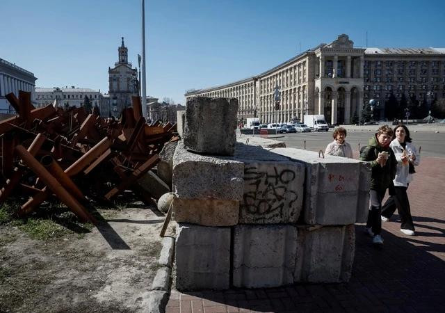 Người dân đi ngang công sự chống tăng tại Kyiv ngày 27.3. ẢNH: REUTERS
