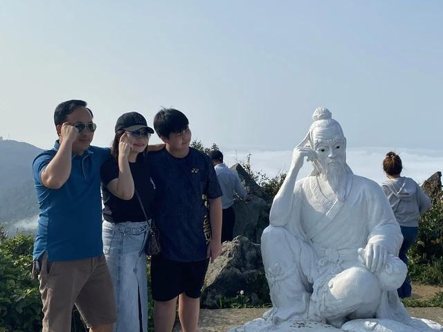 Du khách thích thú check-in cùng tượng tiên ông trên đỉnh Bàn Cờ. Ảnh: THY PHƯỚC