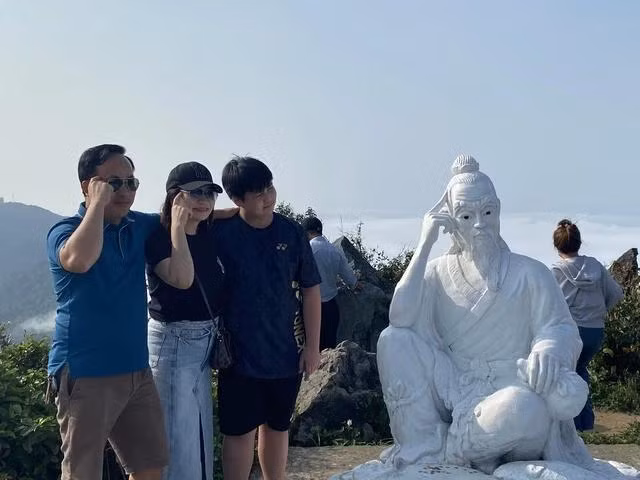 Du khách thích thú check-in cùng tượng tiên ông trên đỉnh Bàn Cờ. Ảnh: THY PHƯỚC